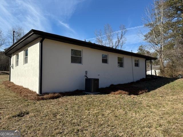 view of side of home with central AC and a lawn