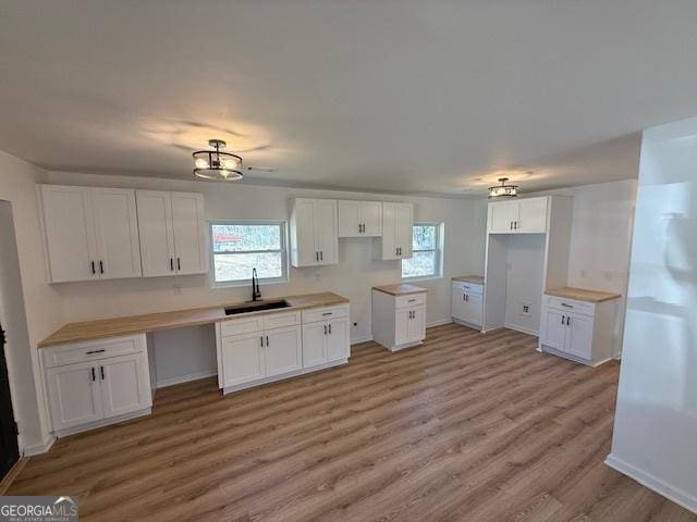 kitchen featuring white cabinetry, sink, and light hardwood / wood-style flooring