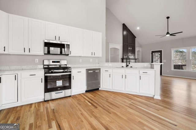 kitchen with sink, white cabinetry, light wood-type flooring, appliances with stainless steel finishes, and kitchen peninsula