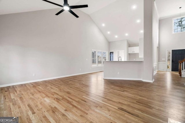 unfurnished living room featuring ceiling fan, high vaulted ceiling, light hardwood / wood-style flooring, and a wealth of natural light