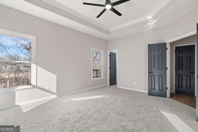 unfurnished bedroom with a raised ceiling, ornamental molding, and carpet