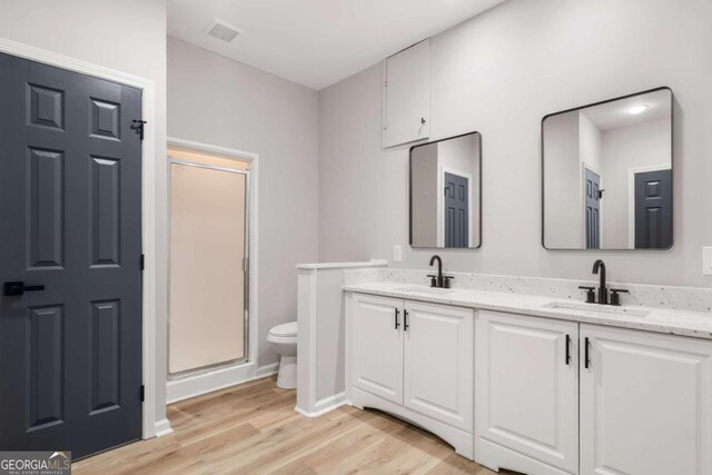 bathroom with hardwood / wood-style flooring, vanity, toilet, and an enclosed shower