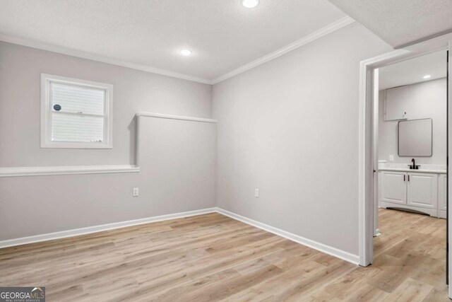 spare room featuring ornamental molding, sink, a textured ceiling, and light hardwood / wood-style flooring