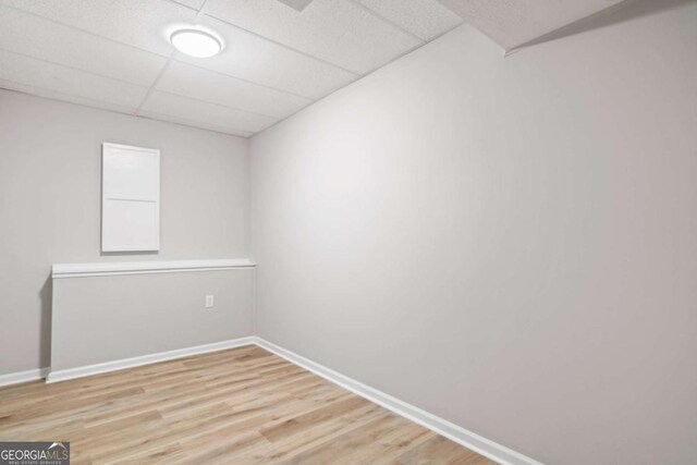 empty room with a drop ceiling and hardwood / wood-style floors