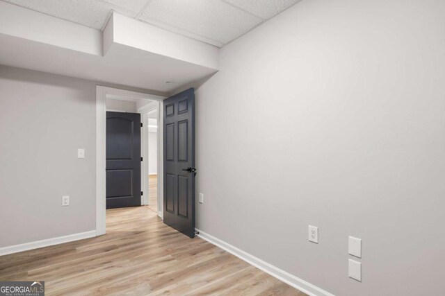 interior space featuring a paneled ceiling and light hardwood / wood-style flooring