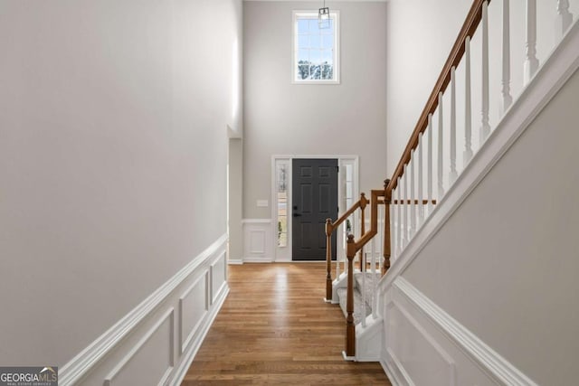 entryway with wood-type flooring and a towering ceiling