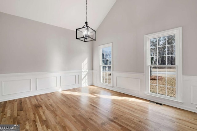 unfurnished dining area featuring vaulted ceiling, a healthy amount of sunlight, and light wood-type flooring