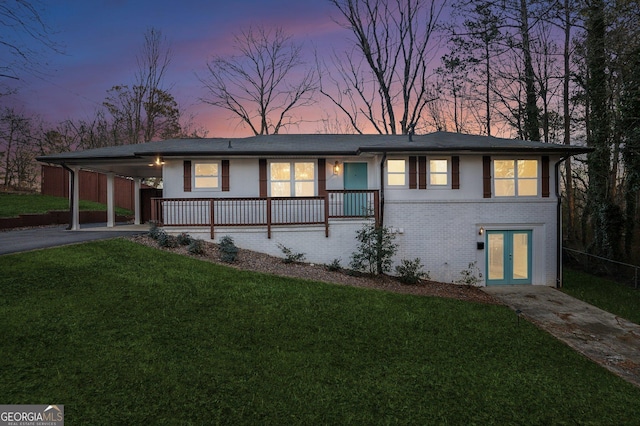 view of front of home with french doors, a carport, and a lawn