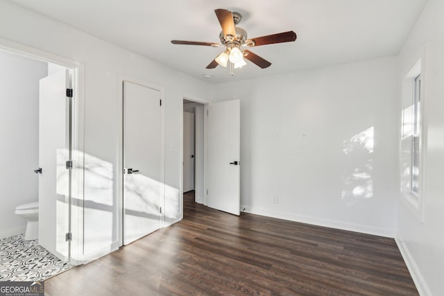 unfurnished bedroom featuring ceiling fan, dark wood-type flooring, and ensuite bath