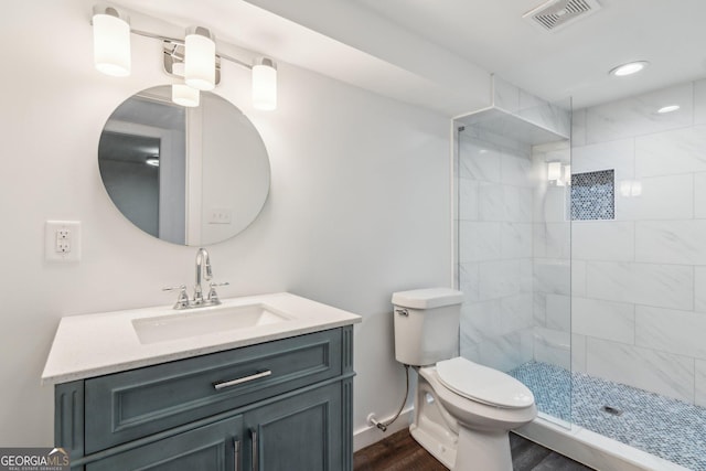 bathroom featuring tiled shower, vanity, toilet, and hardwood / wood-style floors