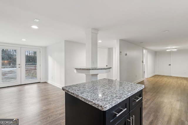 kitchen featuring french doors, dark hardwood / wood-style floors, a center island, and light stone countertops