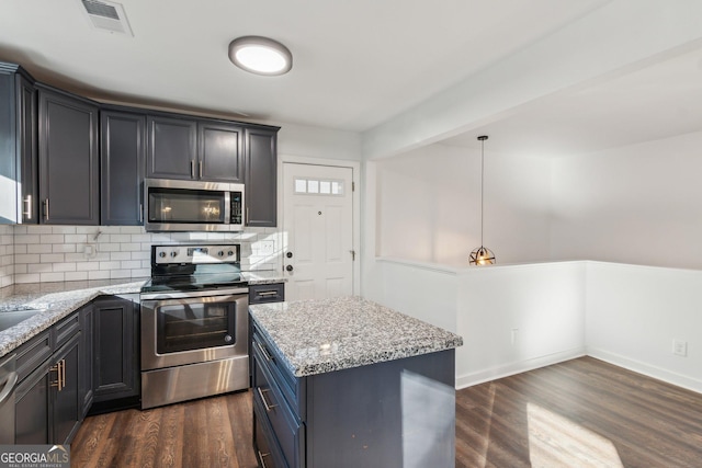 kitchen with stainless steel appliances, a center island, pendant lighting, and light stone counters