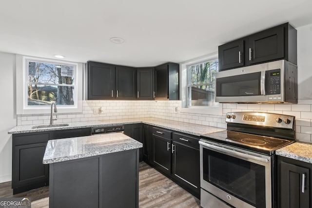 kitchen featuring appliances with stainless steel finishes, hardwood / wood-style floors, sink, decorative backsplash, and a center island