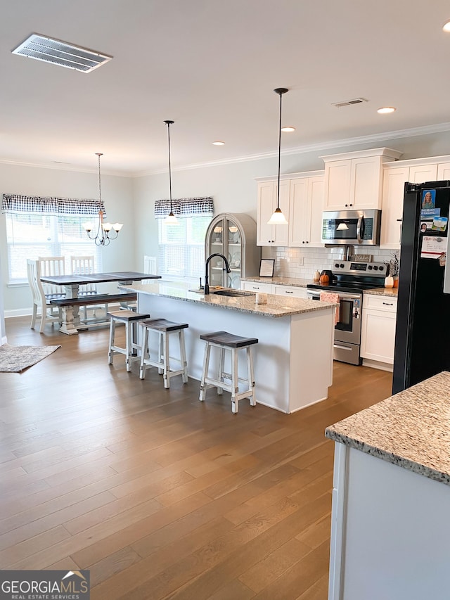 kitchen featuring sink, decorative light fixtures, a center island with sink, appliances with stainless steel finishes, and white cabinets