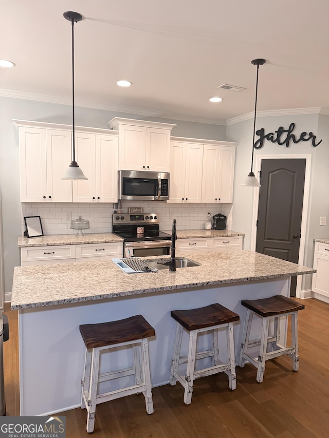 kitchen featuring appliances with stainless steel finishes, pendant lighting, an island with sink, white cabinets, and dark hardwood / wood-style flooring