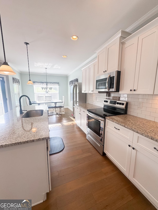 kitchen with crown molding, decorative backsplash, white cabinetry, a sink, and stainless steel appliances