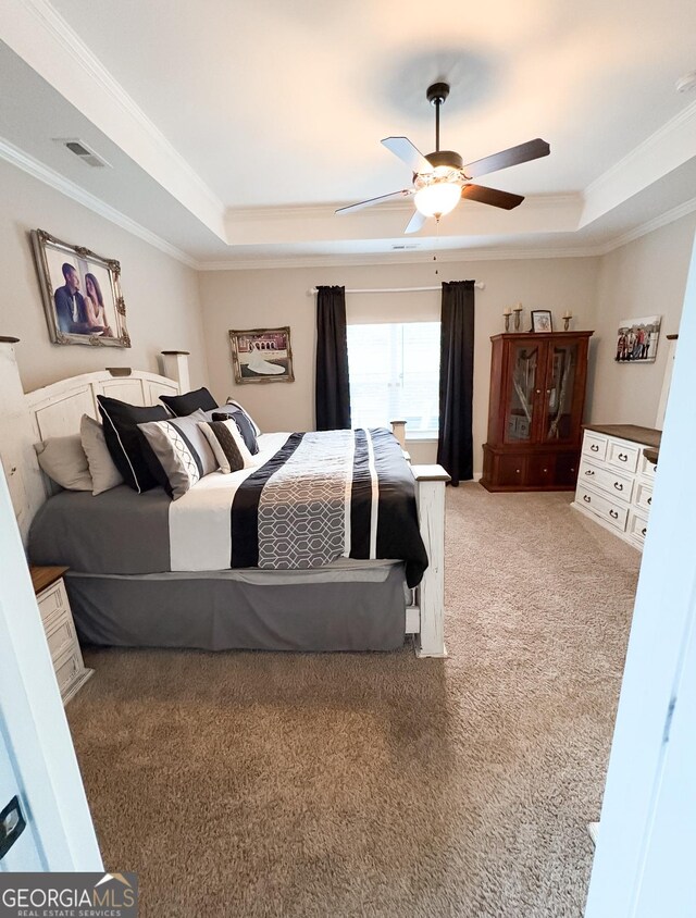 carpeted bedroom with visible vents, crown molding, and a tray ceiling