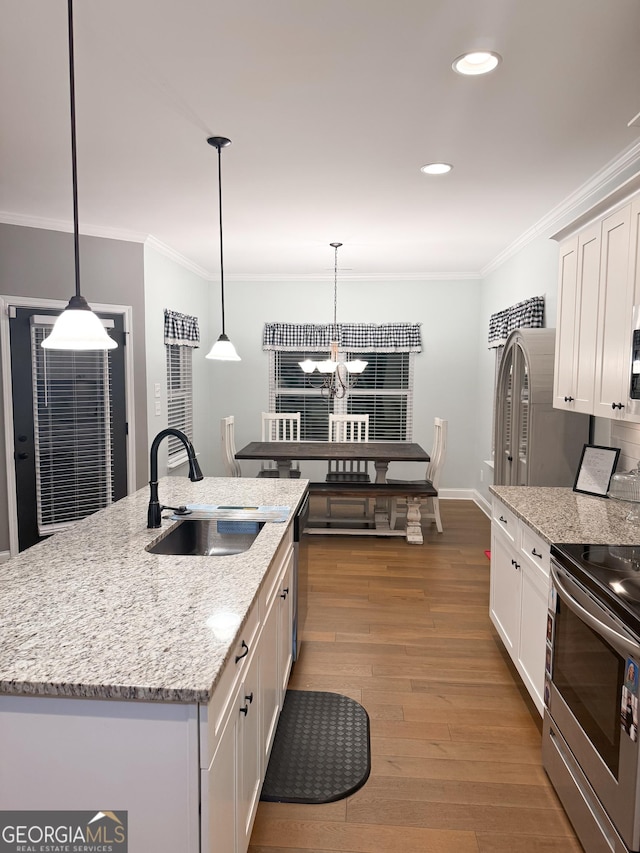 kitchen featuring sink, dark hardwood / wood-style floors, an island with sink, white cabinets, and decorative light fixtures