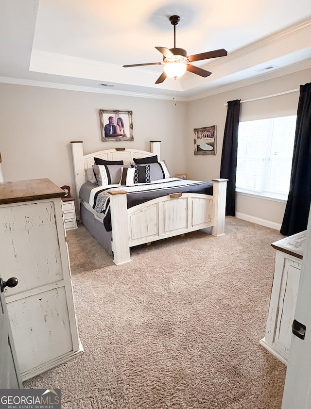 bedroom with light carpet, a ceiling fan, a tray ceiling, visible vents, and ornamental molding