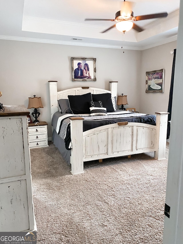 carpeted bedroom featuring ceiling fan, ornamental molding, and a tray ceiling