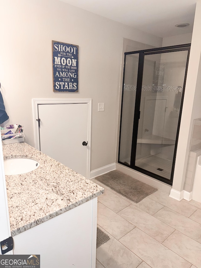 bathroom with vanity, baseboards, a shower stall, and tile patterned floors