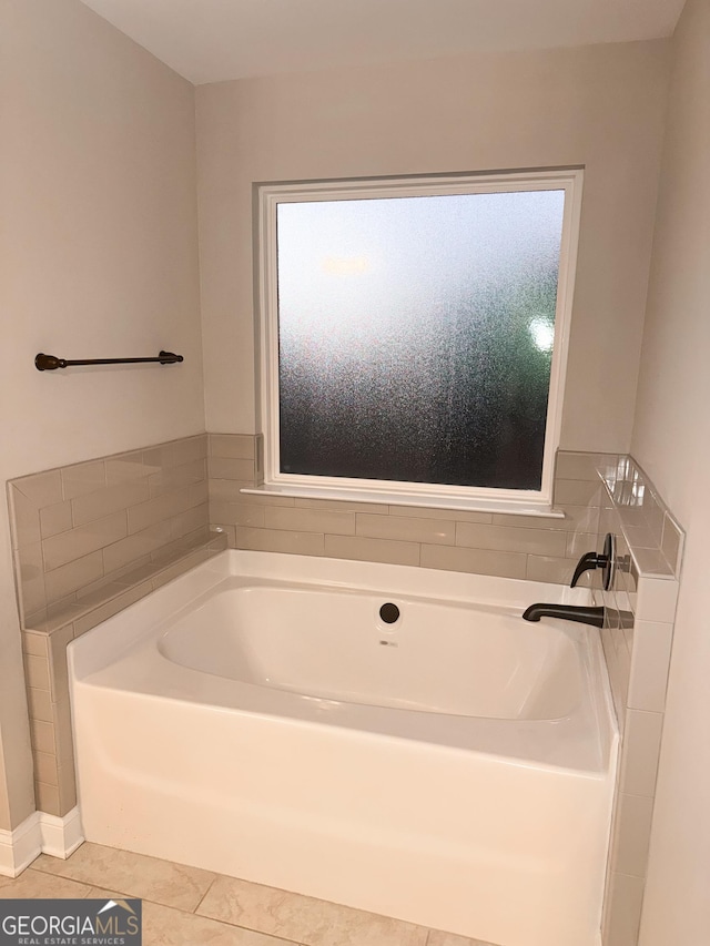 bathroom with tile patterned floors and a bath