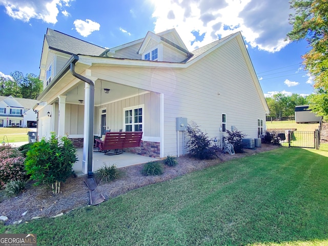 view of property exterior featuring board and batten siding, a lawn, a gate, a patio area, and fence