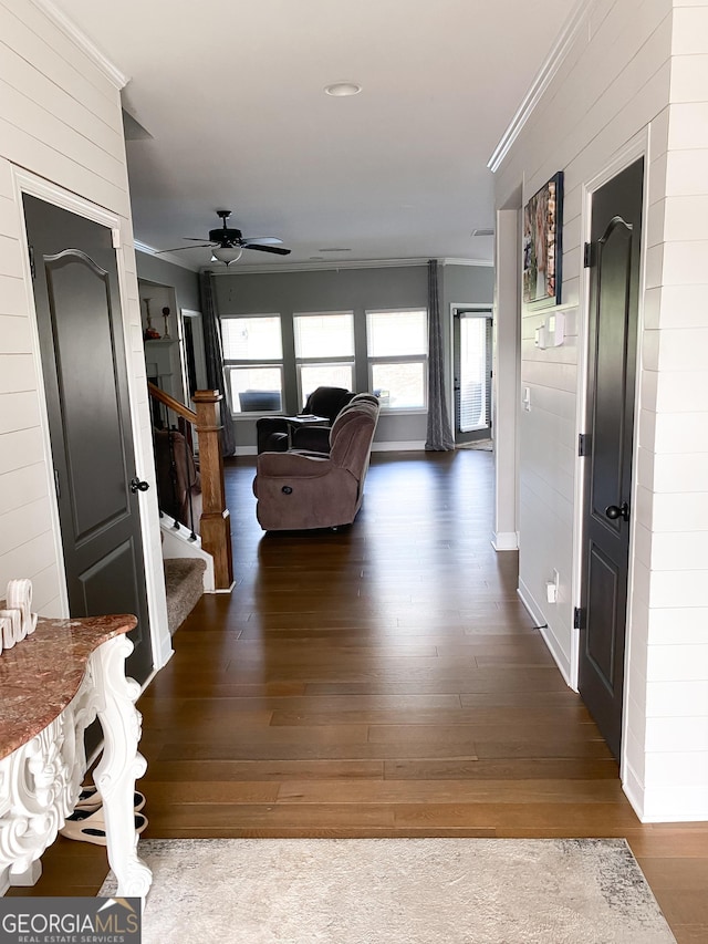 hallway featuring crown molding, baseboards, stairs, and wood finished floors