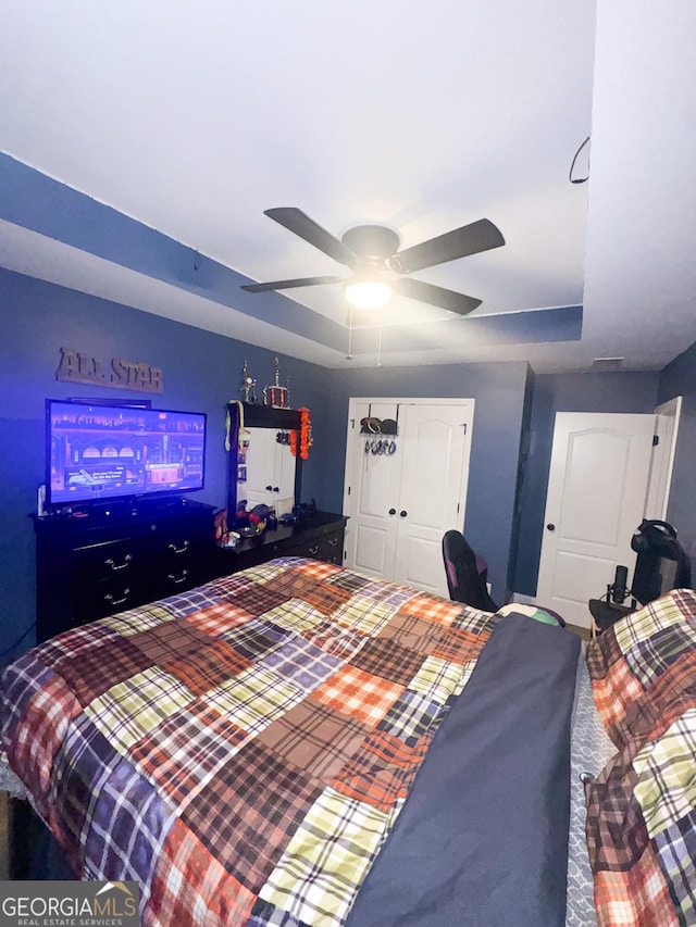 bedroom with ceiling fan, a raised ceiling, and a closet