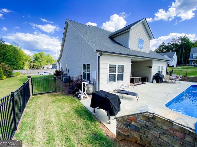 back of property featuring a fenced backyard, a shingled roof, a lawn, and a patio area