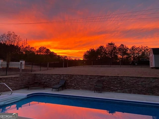 pool at dusk with a fenced in pool and fence