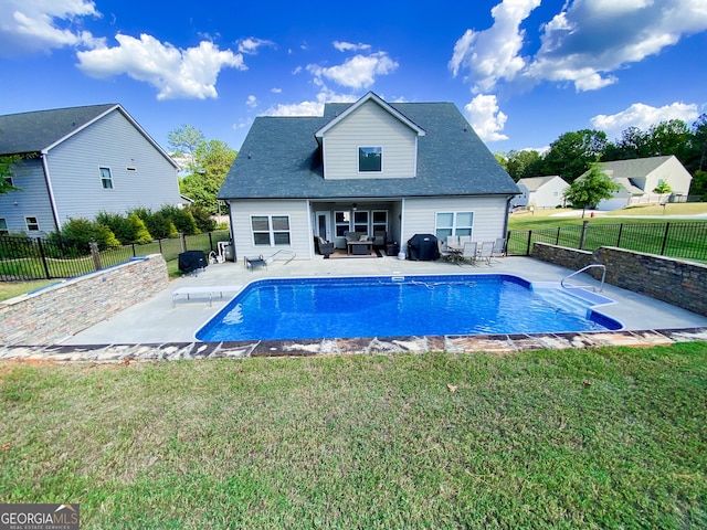 rear view of property featuring a fenced in pool, a patio area, and a lawn