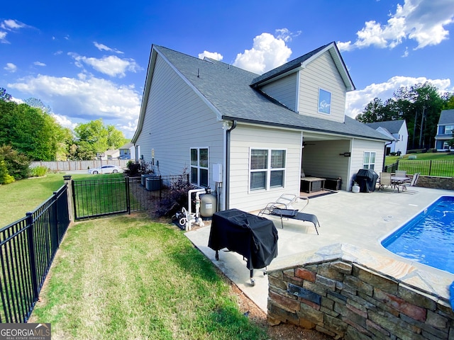 rear view of house featuring ceiling fan, a patio, a fenced in pool, and a lawn