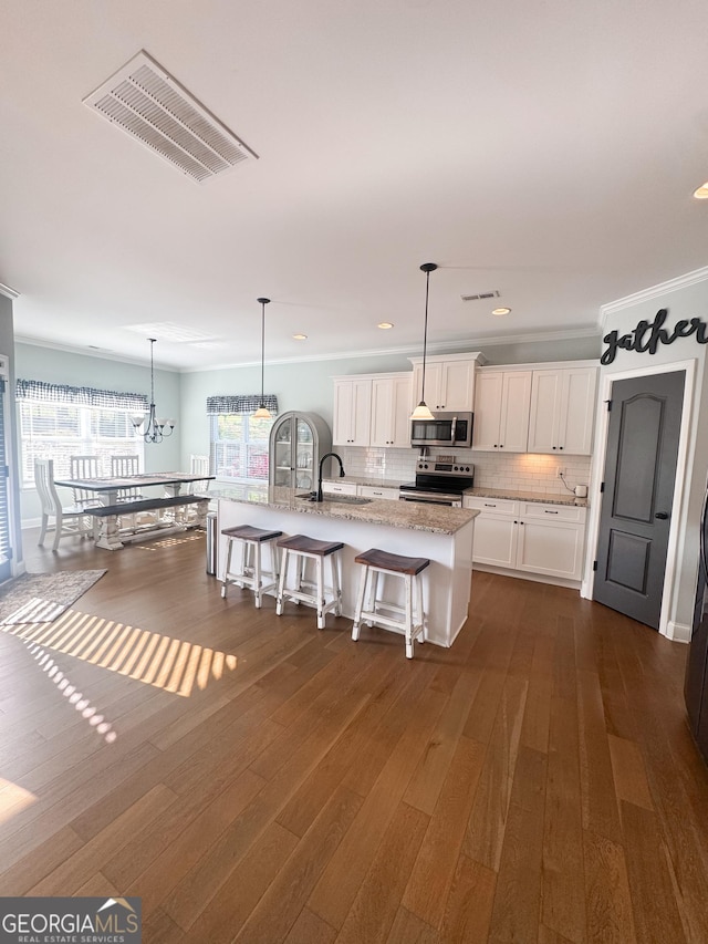 kitchen featuring visible vents, a kitchen breakfast bar, white cabinetry, light stone counters, and stainless steel appliances