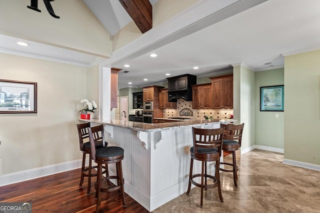 kitchen featuring a breakfast bar, decorative backsplash, kitchen peninsula, light stone countertops, and beam ceiling