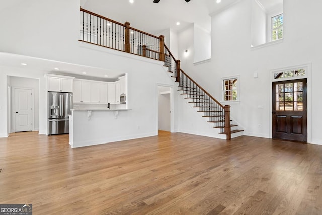 unfurnished living room with light hardwood / wood-style floors and a high ceiling