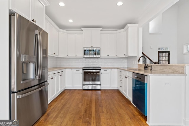 kitchen with white cabinetry, light stone countertops, decorative backsplash, and stainless steel appliances