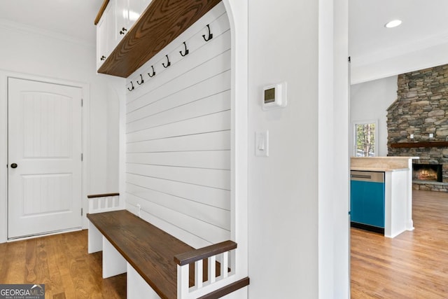 mudroom with crown molding, a fireplace, and light hardwood / wood-style floors