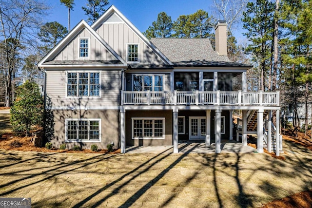 rear view of house with a wooden deck, a patio, a sunroom, and a lawn