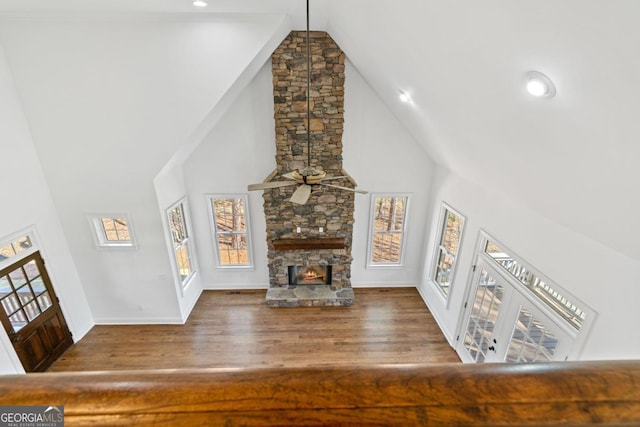 unfurnished living room featuring ceiling fan, a fireplace, high vaulted ceiling, and wood-type flooring