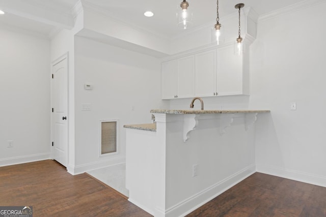 kitchen with pendant lighting, dark wood-type flooring, a breakfast bar area, and white cabinets