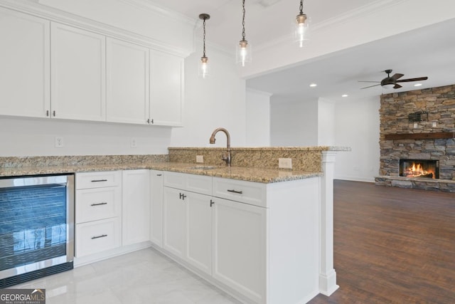 kitchen featuring white cabinetry, sink, beverage cooler, and kitchen peninsula