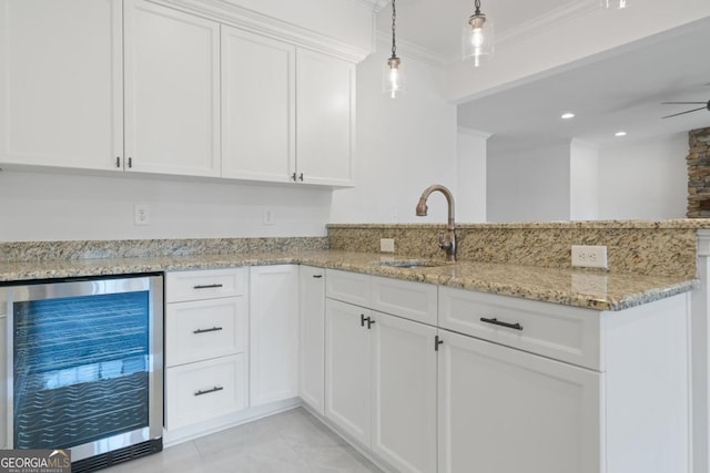 kitchen featuring decorative light fixtures, sink, white cabinets, beverage cooler, and light stone counters