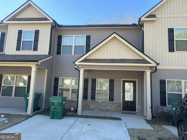 view of front of property featuring covered porch, board and batten siding, and brick siding