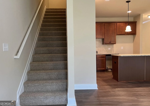 staircase featuring wood finished floors and baseboards