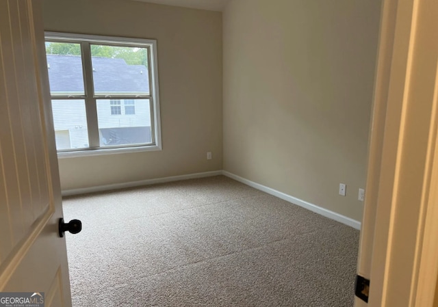 spare room featuring carpet and baseboards