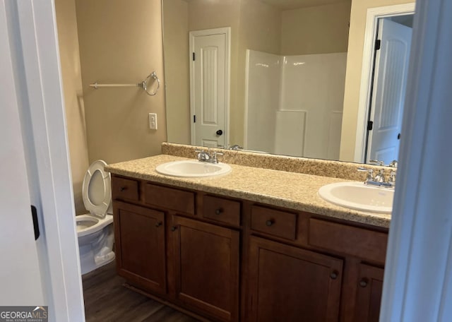 bathroom featuring double vanity, wood finished floors, walk in shower, and a sink