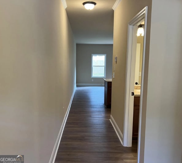 hall with crown molding, baseboards, and dark wood-style flooring