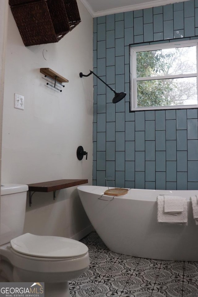 bathroom with tile patterned flooring, ornamental molding, a bath, and toilet