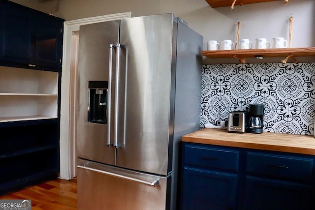 kitchen with blue cabinetry, high quality fridge, butcher block countertops, and hardwood / wood-style floors